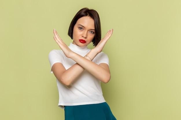 Mujer en blusa blanca y falda verde posign y mostrando el signo de prohibición