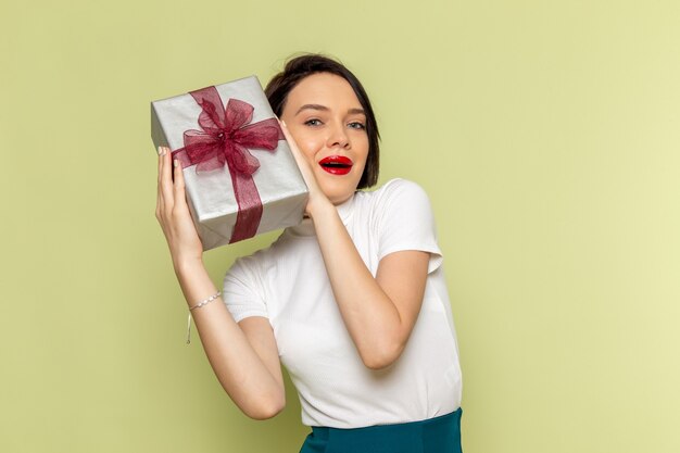 Mujer con blusa blanca y falda verde sosteniendo la caja actual