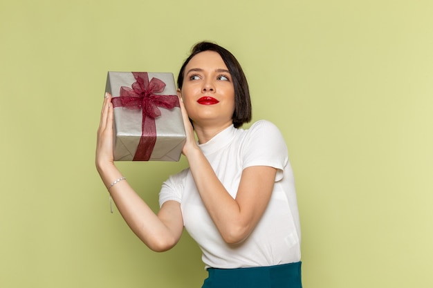 Mujer con blusa blanca y falda verde sosteniendo la caja actual