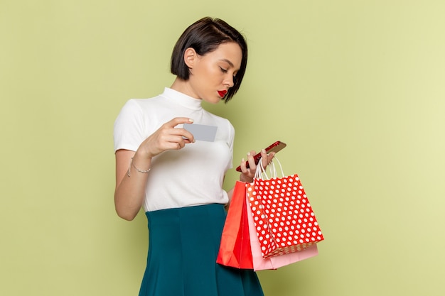 Mujer con blusa blanca y falda verde sosteniendo paquetes de compras