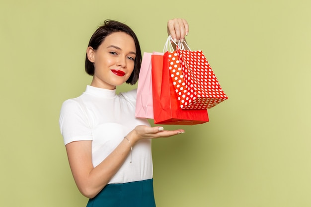 Mujer con blusa blanca y falda verde sosteniendo paquetes de compras