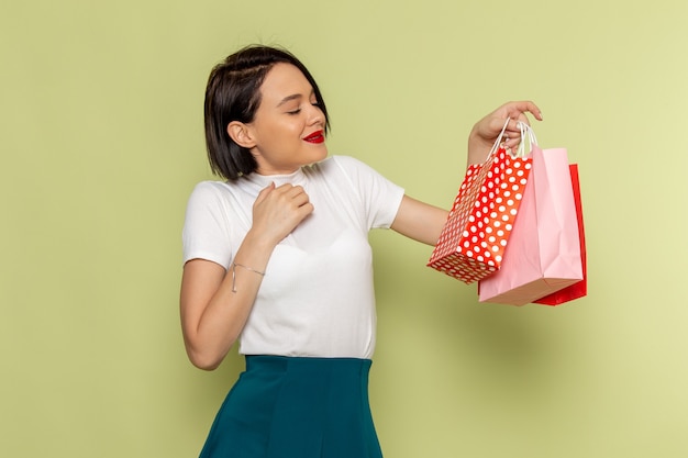 Foto gratuita mujer con blusa blanca y falda verde sosteniendo paquetes de compras