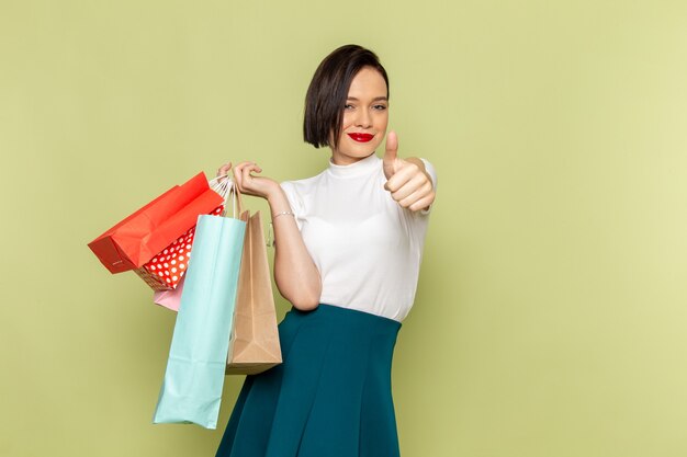 Mujer con blusa blanca y falda verde sosteniendo paquetes de compras