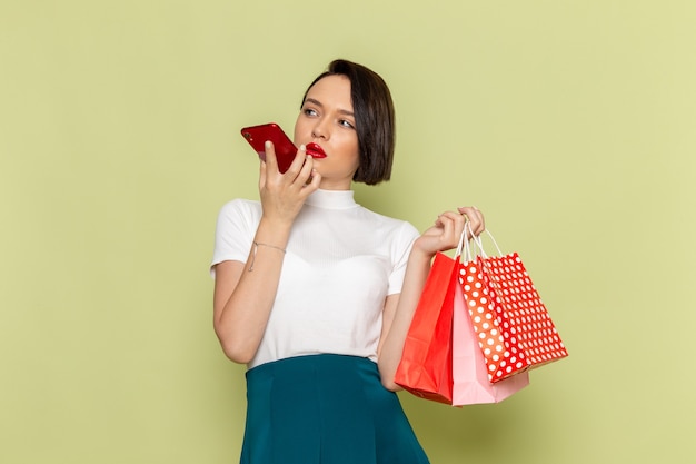 Mujer con blusa blanca y falda verde sosteniendo paquetes de compras