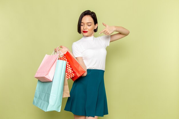 Mujer con blusa blanca y falda verde sosteniendo paquetes de compras