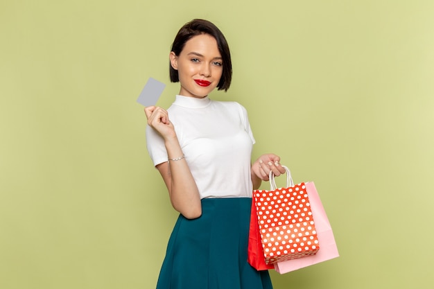 Mujer con blusa blanca y falda verde sosteniendo paquetes de compras