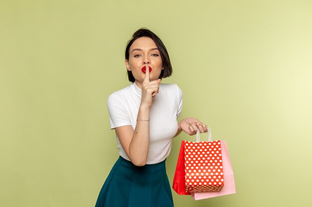 Mujer con blusa blanca y falda verde sosteniendo paquetes de compras