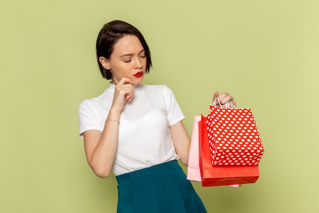 Mujer con blusa blanca y falda verde sosteniendo paquetes de compras