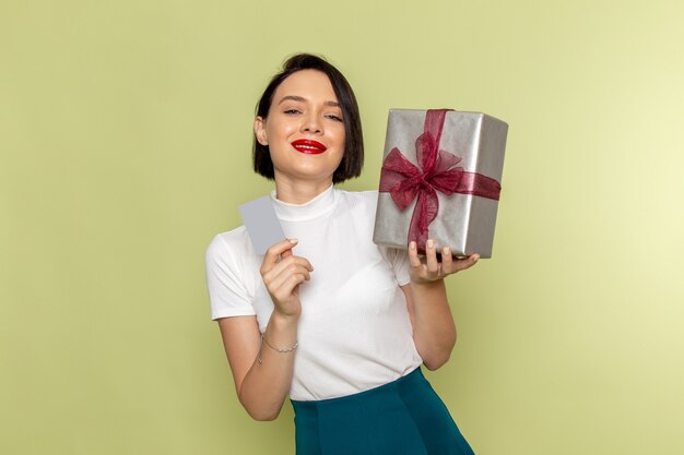 Mujer en blusa blanca y falda verde con tarjeta gris y caja actual