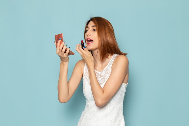 mujer en blusa blanca y jeans azul haciendo maquillaje