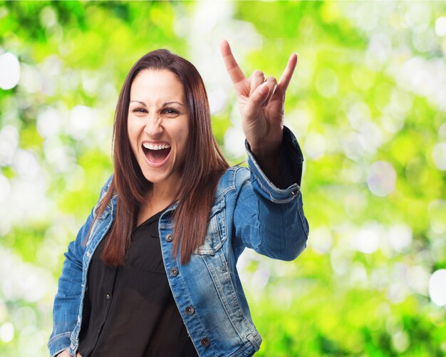 Mujer con la boca abierta haciendo cuernos con la mano