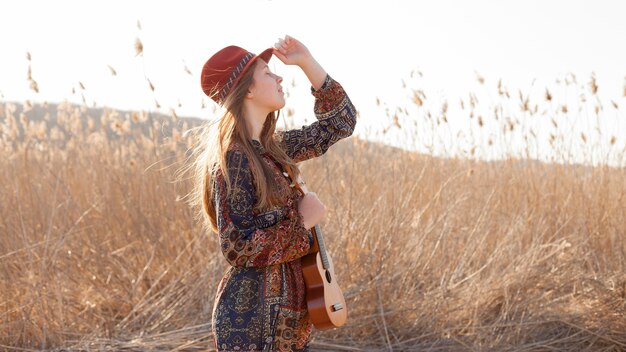 Mujer bohemia en el campo con ukelele