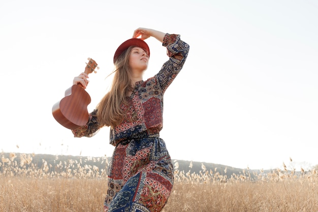 Mujer bohemia en la naturaleza con ukelele