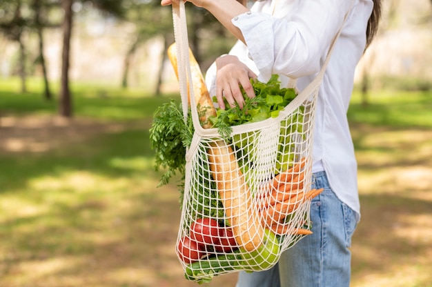 Foto gratuita mujer con bolsa reutilizable en la naturaleza