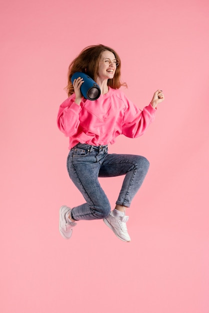 Foto gratuita mujer con bolsas de altavoz saltando