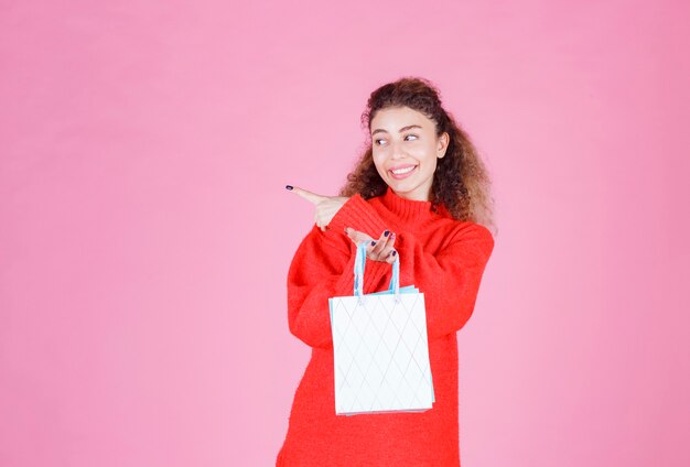 mujer con bolsas de colores apuntando hacia el lado izquierdo.