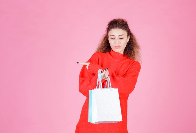 mujer con bolsas de colores apuntando hacia el lado izquierdo.