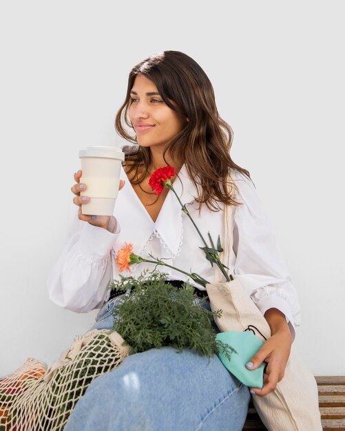 Mujer con bolsas de la compra con café al aire libre