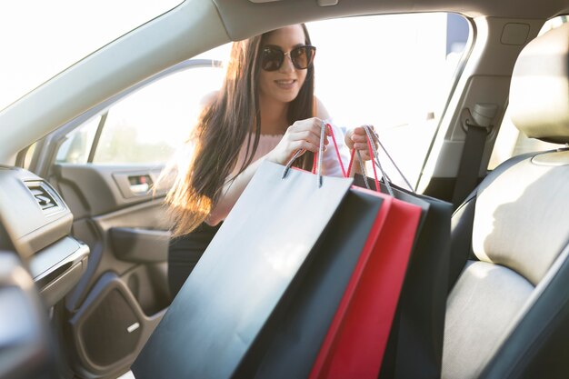 Mujer y bolsas de compras en el coche