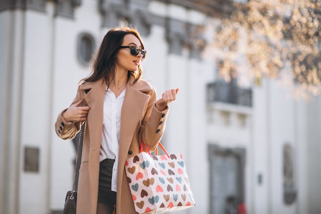 Mujer con bolsas de compras fuera de la calle.