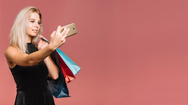 Mujer con bolsas de compras tomando selfie