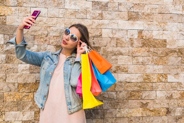 Mujer con bolsas de compras tomando selfie