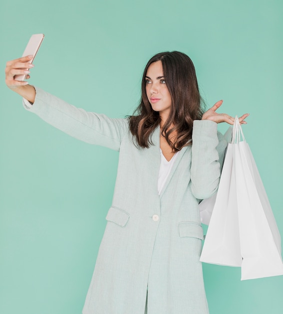 Mujer con bolsas de compras tomando una selfie