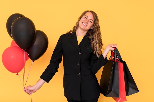 Mujer con bolsas negras y rojas con globos