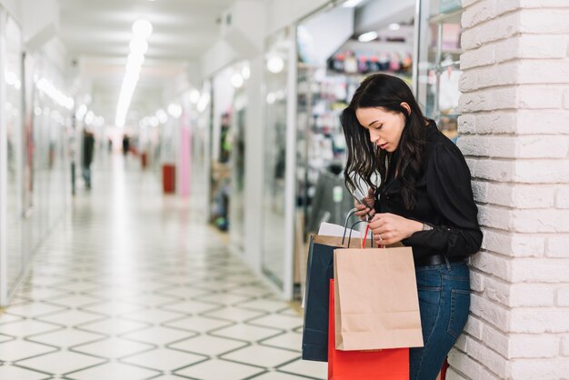 Mujer con bolsas de papel en moderno centro comercial