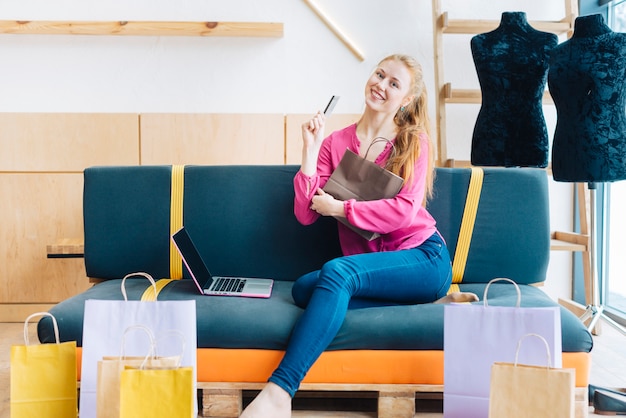 Foto gratuita mujer con bolsas de papel y tarjeta de crédito cerca de la computadora portátil