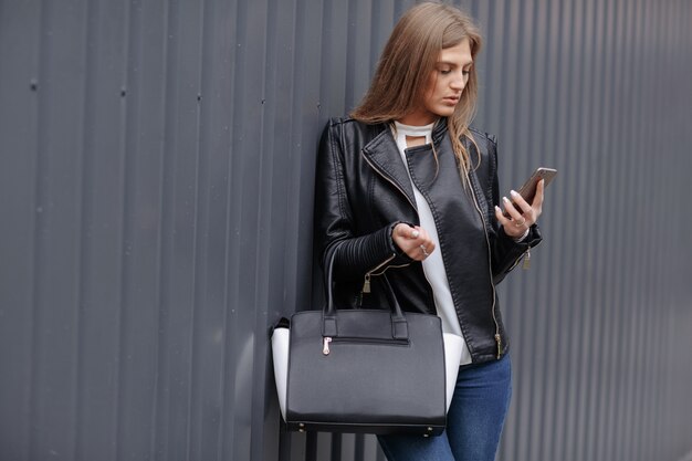 Mujer con bolso mirando su teléfono móvil