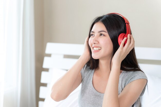 Mujer bonita adolescente asiática con auriculares bluetooth rojos, baile y smiley para escuchar música alegre