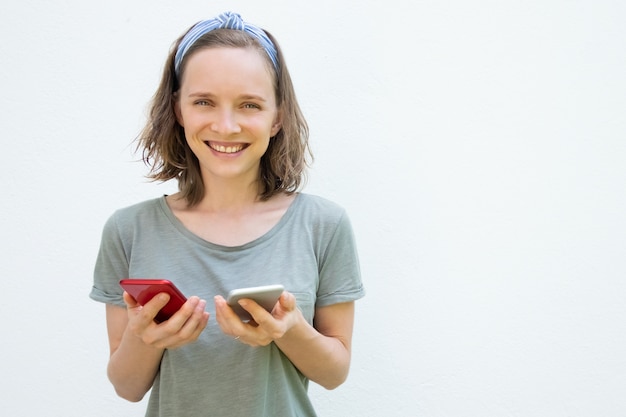 Mujer bonita alegre en ropa de verano con dos teléfonos