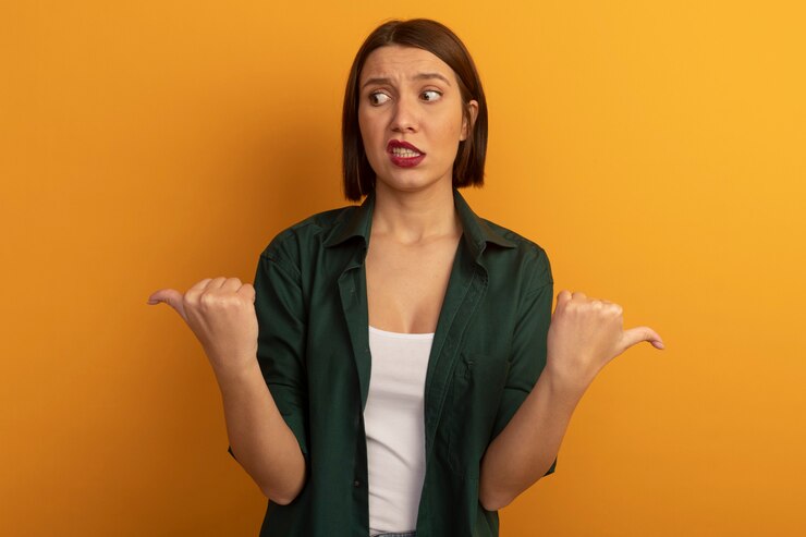 Foto gratuito mujer bonita ansiosa apunta a los lados aislados en la pared naranja