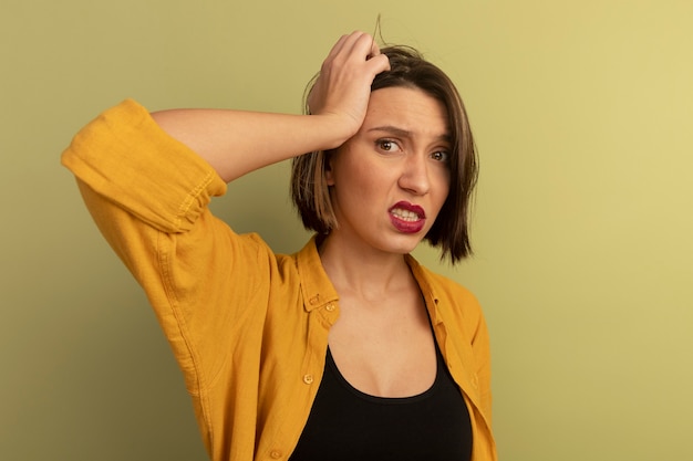 Foto gratuita mujer bonita ansiosa pone la mano en la cabeza aislada en la pared verde oliva