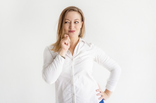 Mujer bonita astuta que toca la barbilla y que mira para otro lado