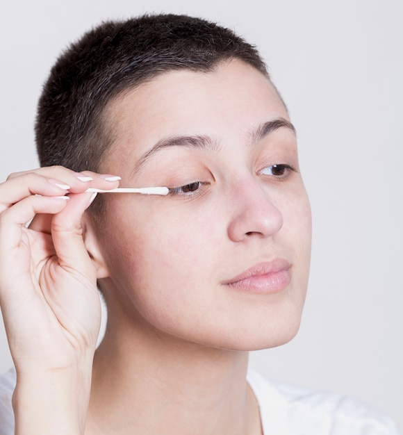 Mujer bonita con un bastoncillo de algodón para limpiar su maquillaje