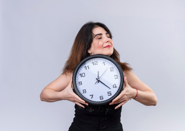 Mujer bonita en blusa negra abrazando felizmente el reloj