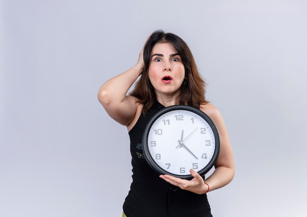 Mujer bonita en blusa negra con reloj mirando preocupado por llegar tarde