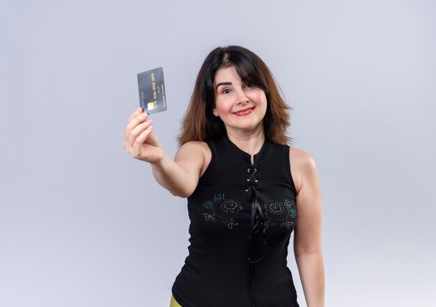 Mujer bonita en blusa negra sonriendo y mostrando su tarjeta