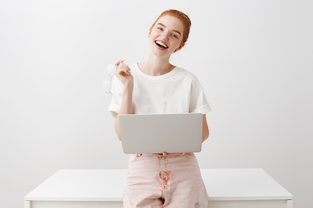 Mujer bonita con cabello rojo usando laptop y sonriendo