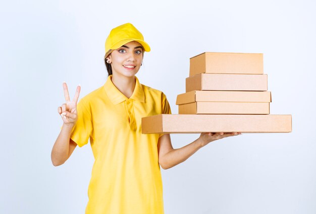 Una mujer bonita con cajas de papel artesanales en blanco marrón que muestran el signo de la victoria.