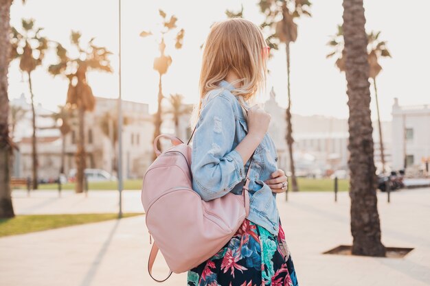 Mujer bonita caminando en las calles de la ciudad con una elegante chaqueta de mezclilla de gran tamaño, sosteniendo una mochila de cuero rosa, tendencia de estilo veraniego