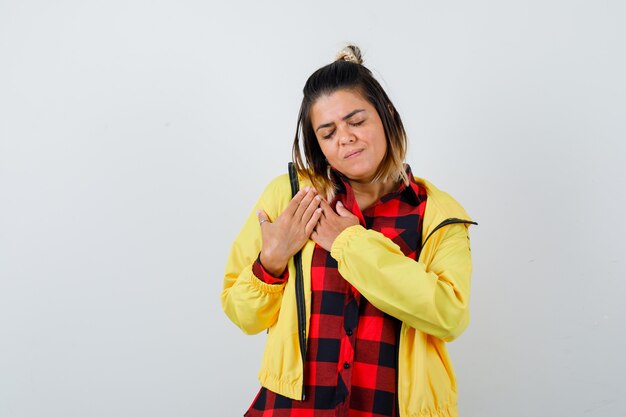 Mujer bonita en camisa, chaqueta cogidos de la mano en el pecho y mirando agradecido, vista frontal.