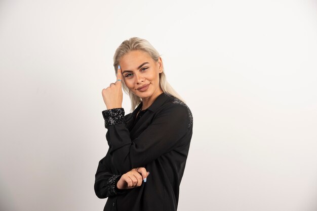 Mujer bonita en camisa negra posando sobre fondo blanco. Foto de alta calidad