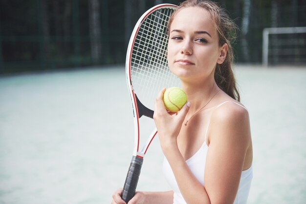 Una mujer bonita con una cancha de tenis de ropa deportiva en la cancha.