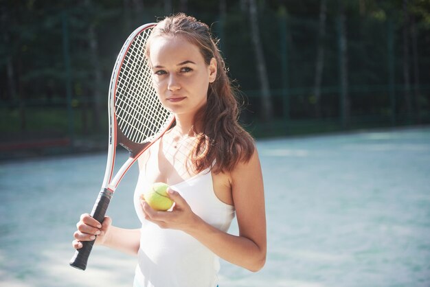 Una mujer bonita con una cancha de tenis de ropa deportiva en la cancha.