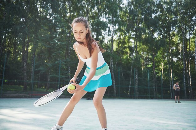 Una mujer bonita con una cancha de tenis de ropa deportiva en la cancha.