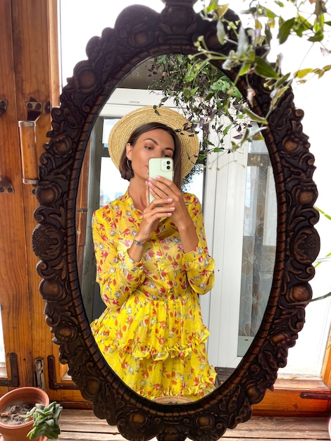 Una mujer bonita en casa toma una foto selfie en el espejo del teléfono móvil para historias y publicaciones en las redes sociales