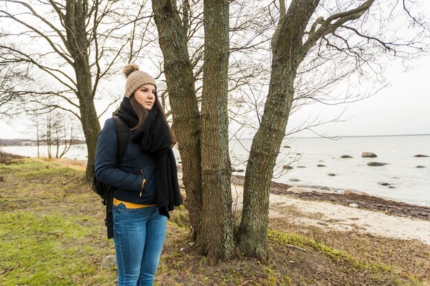 Mujer bonita cerca de árbol en la costa